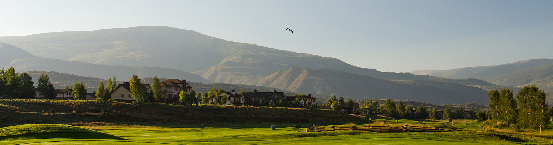 pano view of golf course with mountains in the background